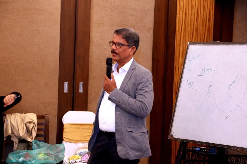 Expert speaker at WiseWealth event — man in gray blazer with microphone, whiteboard with notes visible behind